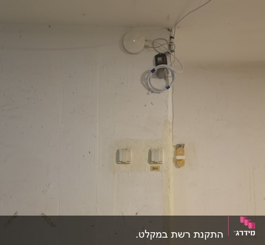 ציוד רשת מותקן על קיר עם חוטים ושקעי חשמל